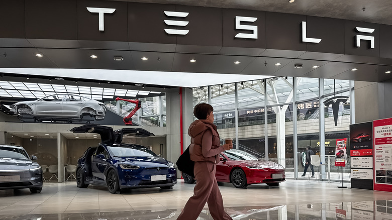 A woman walks past a Tesla showroom inside Chongqing MixC, featuring multiple Tesla electric vehicles on display, including a Model X with its falcon-wing doors open, on March 1, 2025 in Chongqing, China.