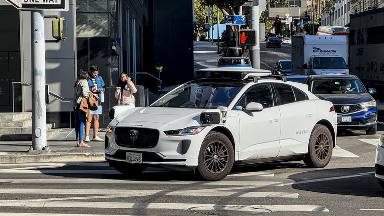 A Waymo autonomous taxi picks up passengers in Downtown Los Angeles.